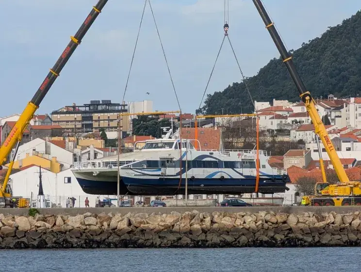 Duas gruas elevam um catamarã na frente ribeirinha de Viana do Castelo